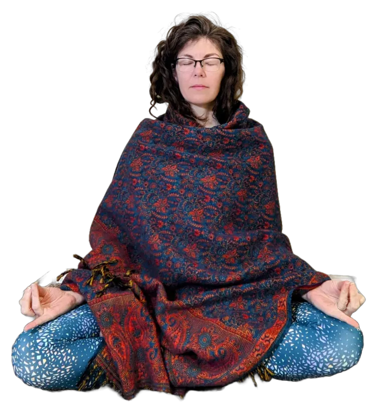 Mel seated in a cross-legged meditation pose, wrapped in a shawl